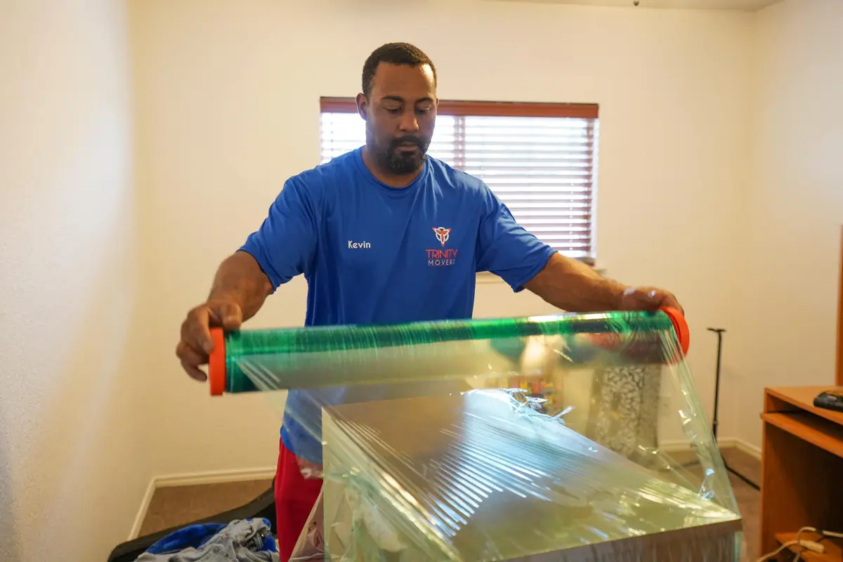 Kevin Joshua of Trinity Movers stretch-wrapping a piece of furniture inside a home