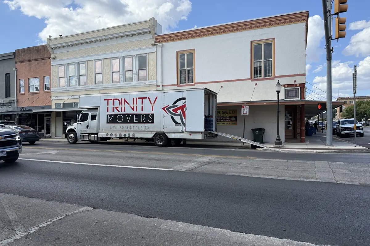 Trinity Movers 26-foot box truck parked along a downtown New Braunfels street lined with historic storefronts